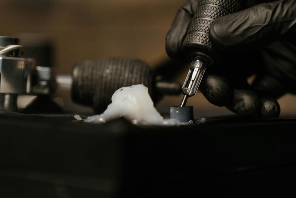 Detailed close-up of a tattoo needle with black gloves in a tattoo studio.